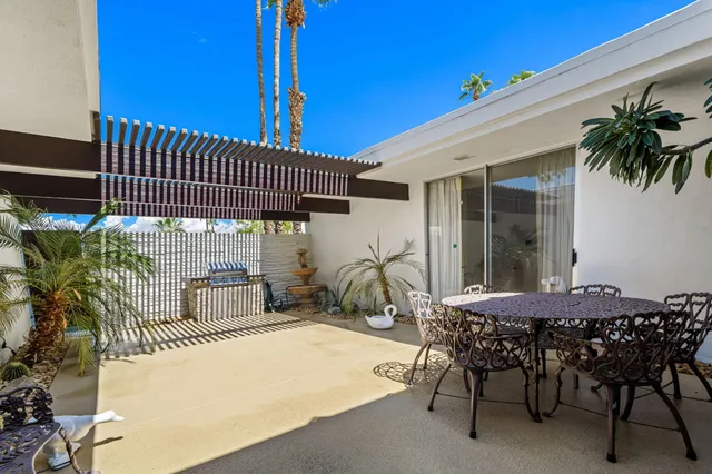 a patio with a table and chairs and potted plants