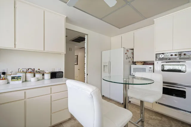 a kitchen with stainless steel appliances a refrigerator a stove a sink and white cabinets with wooden floor