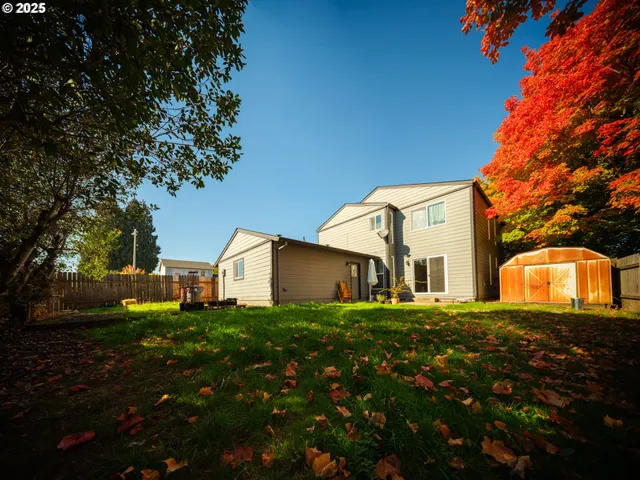 a view of a house with a big yard and large tree