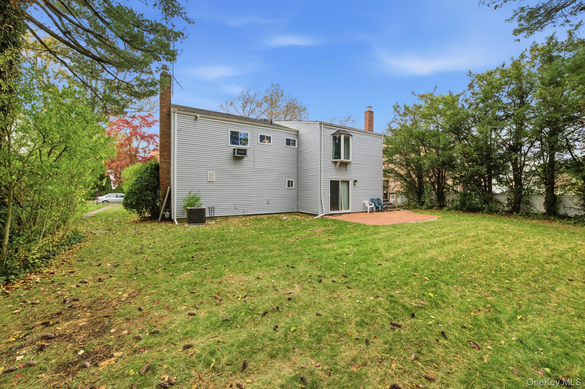 18 Dunhill Road Manhasset Hills, NY 11040 - Photo 20 of 20 a view of a white house with a big yard and large trees