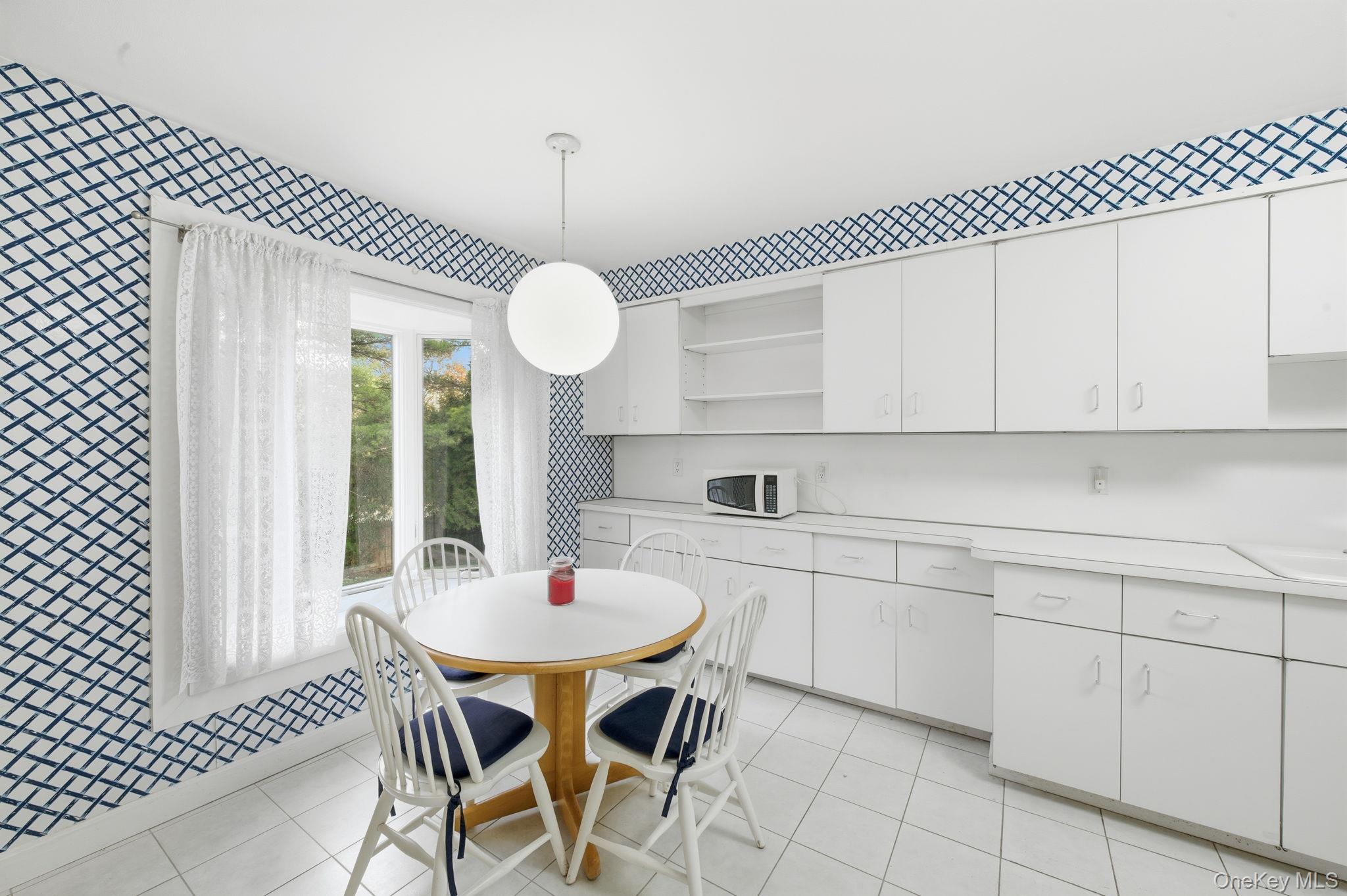 18 Dunhill Road Manhasset Hills, NY 11040 - Photo 8 of 20 a kitchen with white cabinets a table and chairs