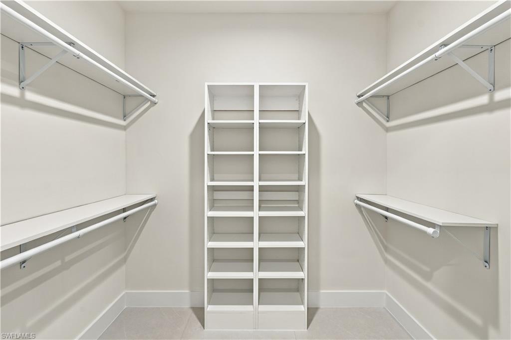 183 5th Street Southwest Naples, FL 34117 - Photo 8 of 40 Walk-in closet featuring built-in shelving, multiple hanging rods, and light-colored walls