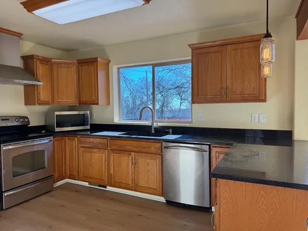 a kitchen with stainless steel appliances granite countertop a sink a stove and a microwave