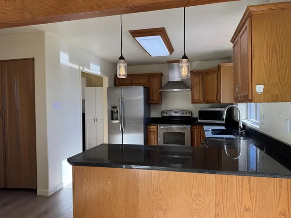 a kitchen with stainless steel appliances granite countertop a sink a stove and a refrigerator