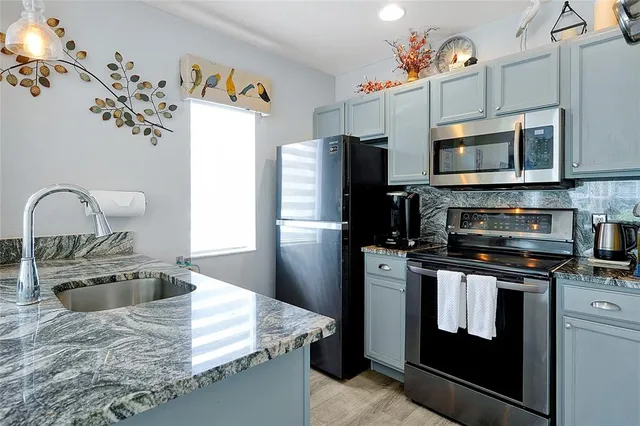 a kitchen with granite countertop a refrigerator stove and microwave