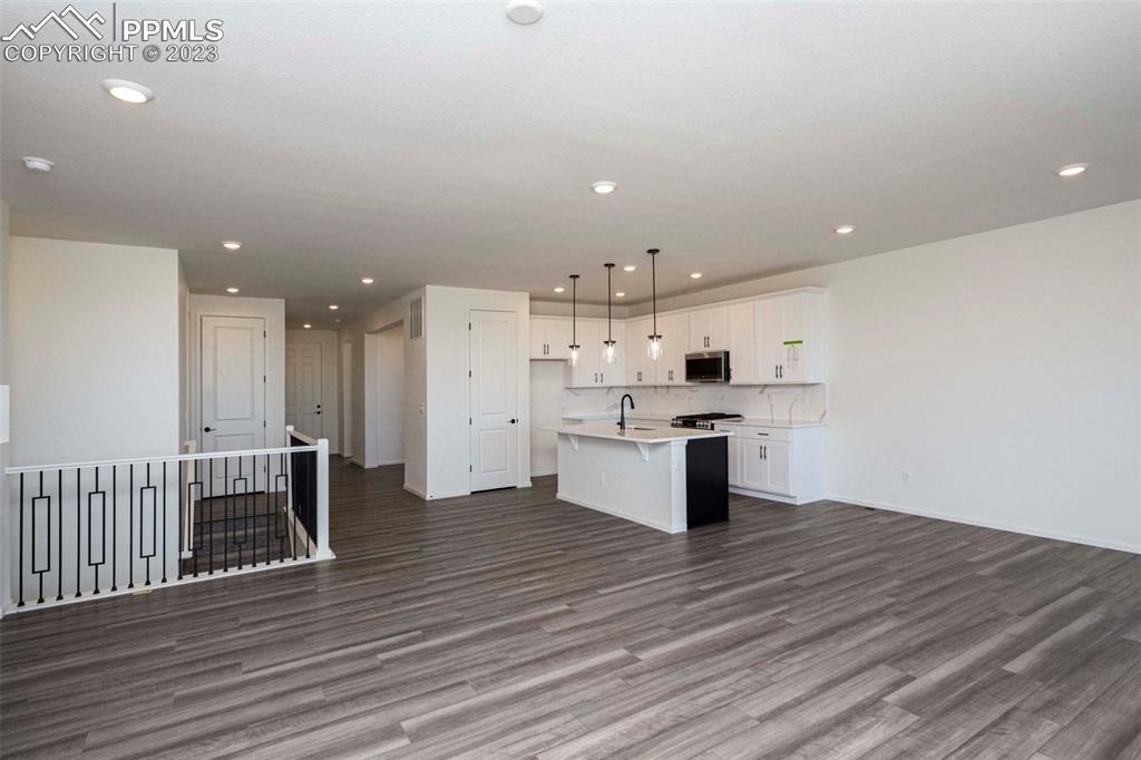 2120 Peachleaf Loop Castle Rock, CO 80108 - Photo 10 of 28 a kitchen with stainless steel appliances kitchen island wooden floors and white cabinets