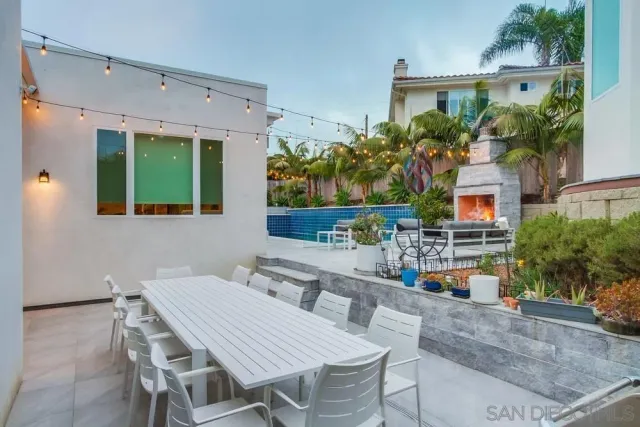 a patio with table and chairs and potted plants