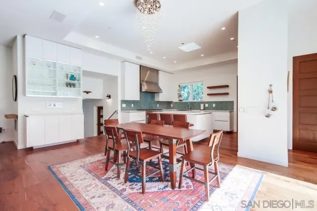 a kitchen with stainless steel appliances a dining table chairs and wooden floor