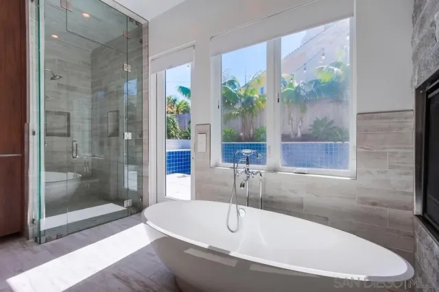 a white bath tub sitting in a bathroom next to a window