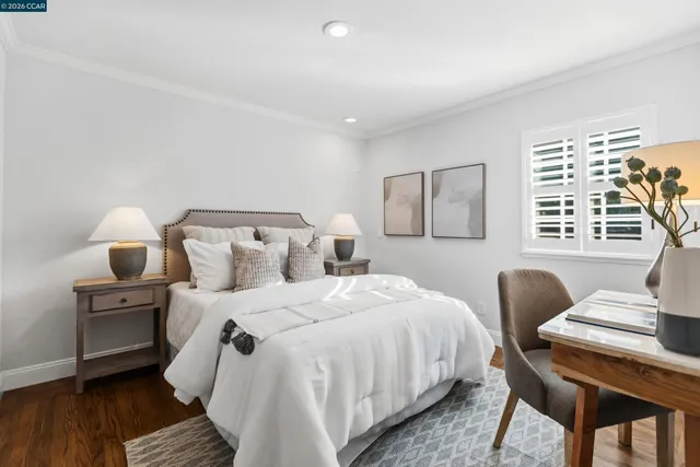 a bedroom with bed and a chair with wooden floor