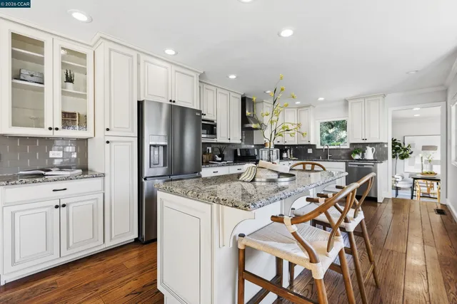 a kitchen with stainless steel appliances granite countertop a table chairs sink refrigerator and cabinets