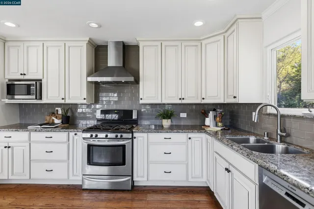 a kitchen with granite countertop white cabinets and appliances