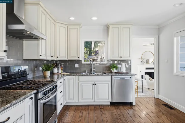 a kitchen with granite countertop a sink cabinets stainless steel appliances and wooden floor