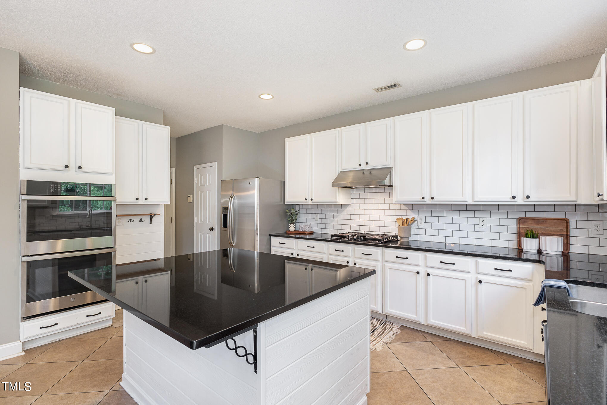 8814 Elizabeth Bennet Place Raleigh, NC 27616 - Photo 14 of 28 a kitchen with kitchen island granite countertop a stove sink and refrigerator