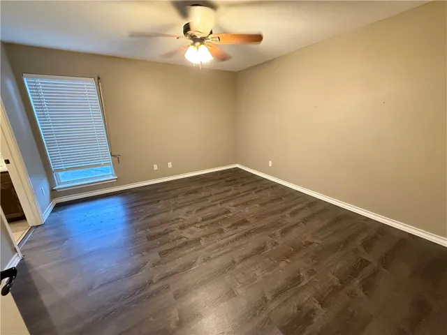 an empty room with wooden floor and fan