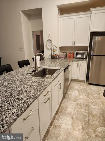 a large kitchen with kitchen island granite countertop a sink and white cabinets