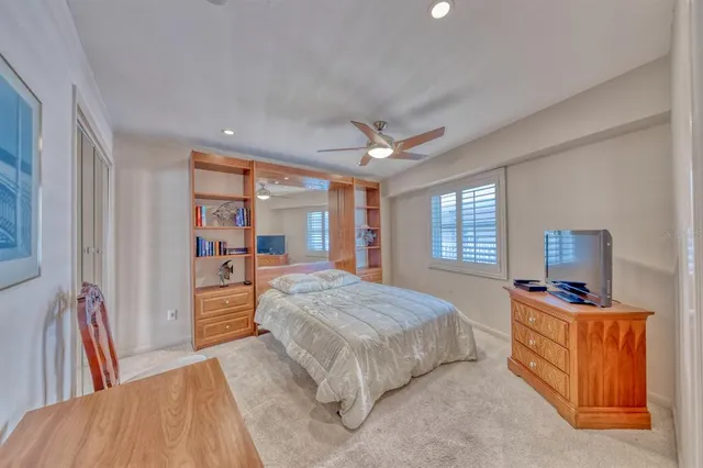 a spacious bedroom with a bed a dresser and a chandelier
