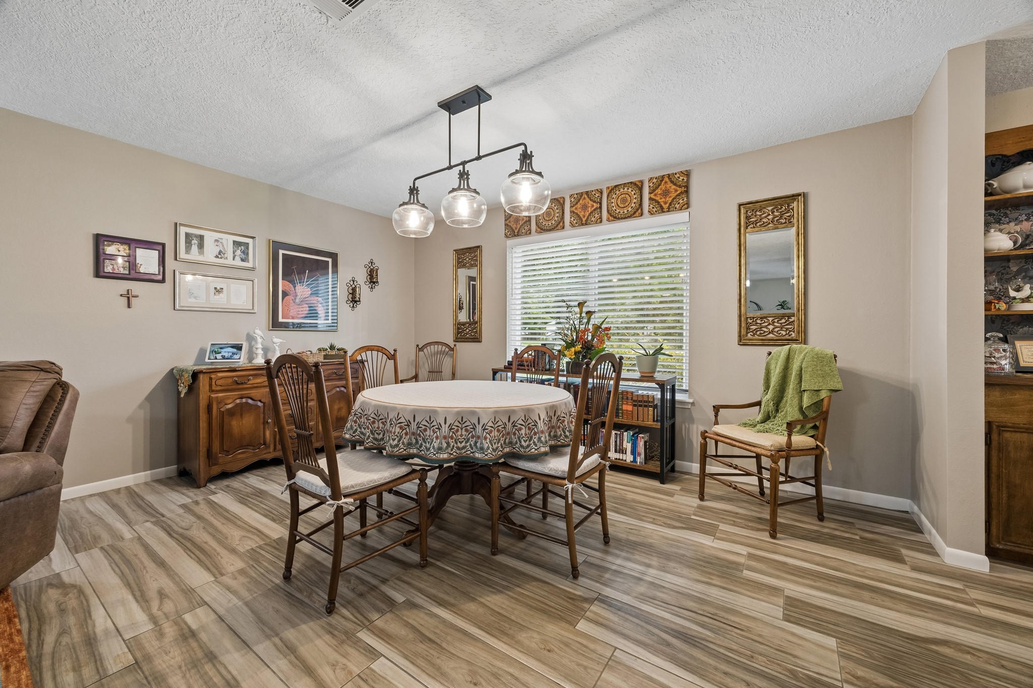 2102 Casa Rio Circle Dickinson, TX 77539 - Photo 5 of 22 Dedicated dining area located just off the living room, creating an ideal space for everyday meals and entertaining. A stylish updated light fixture serves as a focal point above the dining table. Beautiful view of the green space through the window. You will love the way it fills the space with natural light. ***Bonus ~ Dining room light fixture recently replaced by Seller***