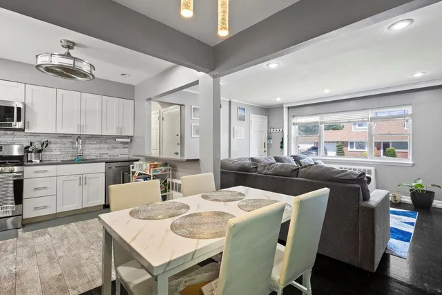 a kitchen with stainless steel appliances kitchen island granite countertop a stove a sink a dining table and chairs