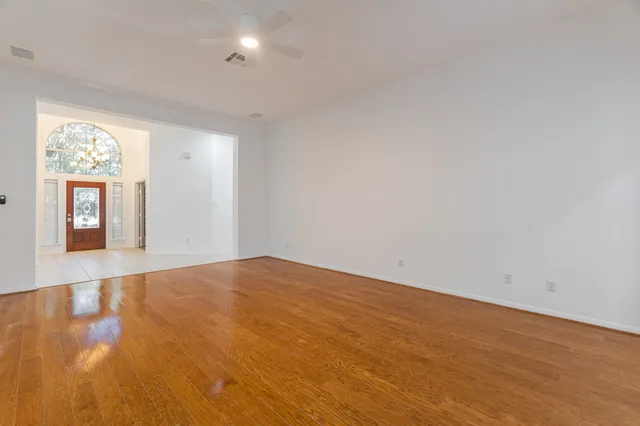 a view of an empty room with wooden floor and windows