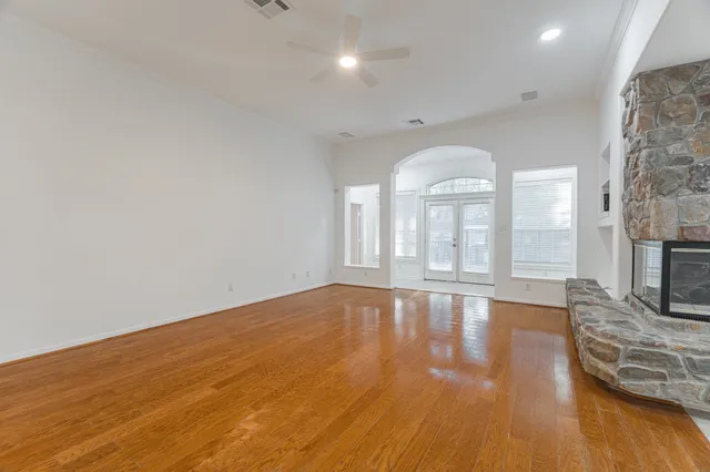 a view of an empty room with wooden floor and a fireplace