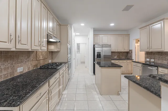 a kitchen with stainless steel appliances granite countertop a stove a sink and a refrigerator