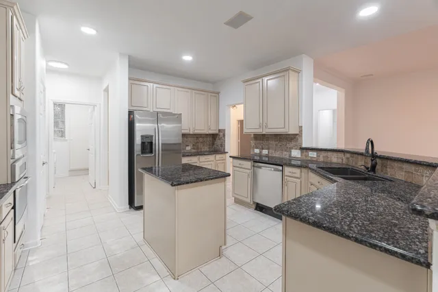 a kitchen with granite countertop a sink stainless steel appliances and white cabinets