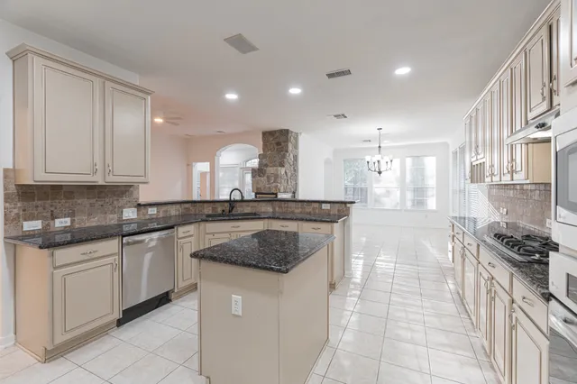 a kitchen with stainless steel appliances granite countertop a stove a sink and a refrigerator