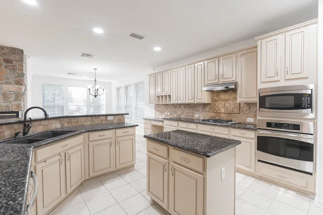 a kitchen with stainless steel appliances granite countertop a sink stove and cabinets