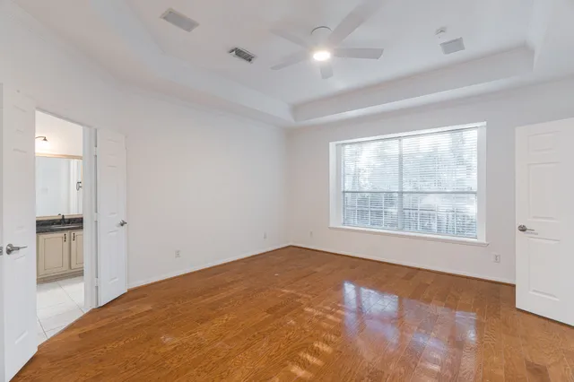 a view of an empty room with a window and wooden floor