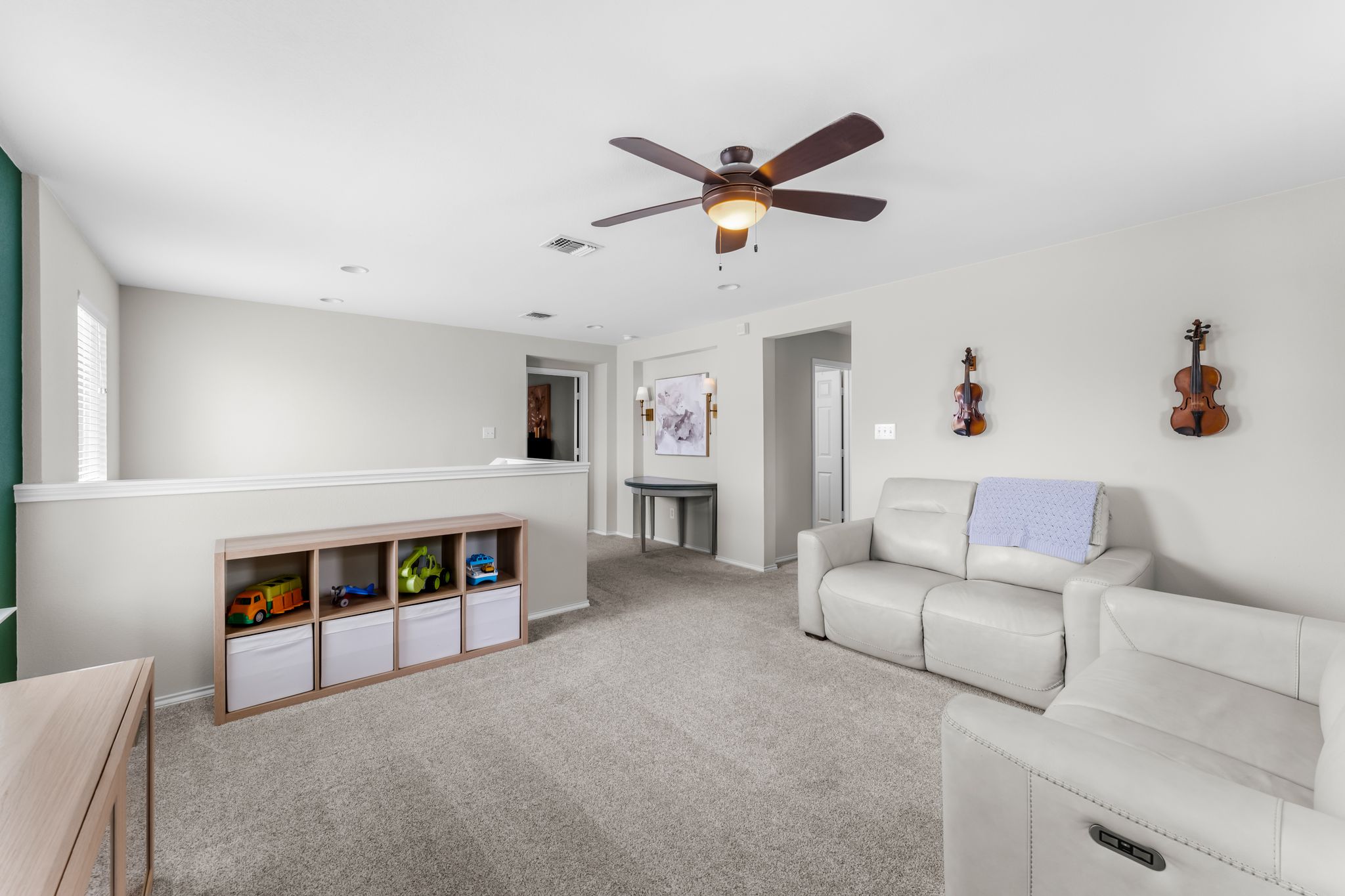 1133 Yellow Iris Road Leander, TX 78641 - Photo 26 of 37 Expansive carpeted room featuring a ceiling fan with integrated lighting, a half-wall partition, and a light-colored accent wall