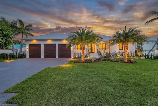 a view of a house with a yard and palm trees