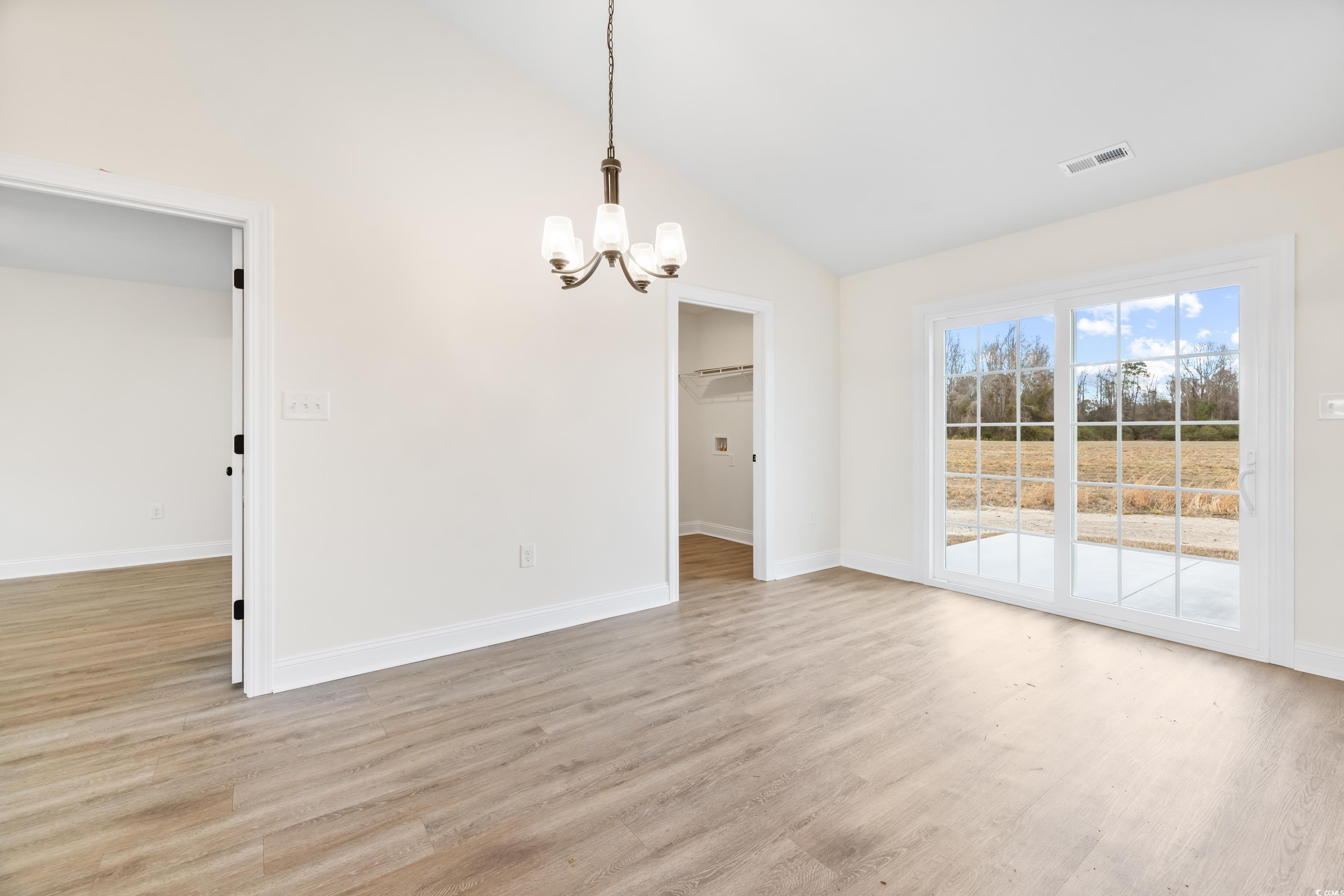 3640 Bethel Chapel Road Loris, SC 29569 - Photo 16 of 35 Unfurnished dining area with vaulted ceiling, a chandelier, and light wood-style flooring