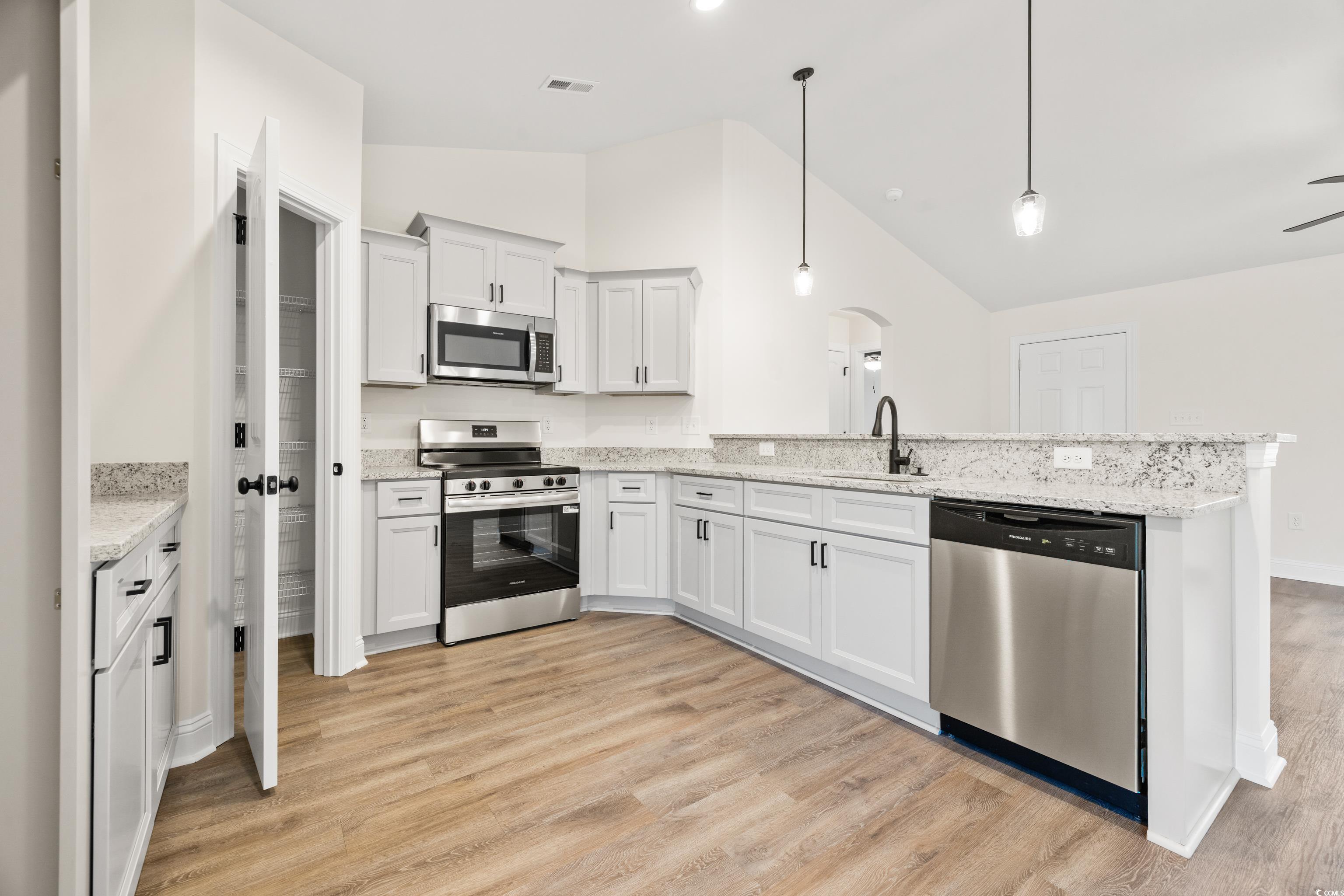 3640 Bethel Chapel Road Loris, SC 29569 - Photo 18 of 35 Kitchen with stainless steel appliances, a peninsula, hanging light fixtures, white cabinetry, and light wood-style floors