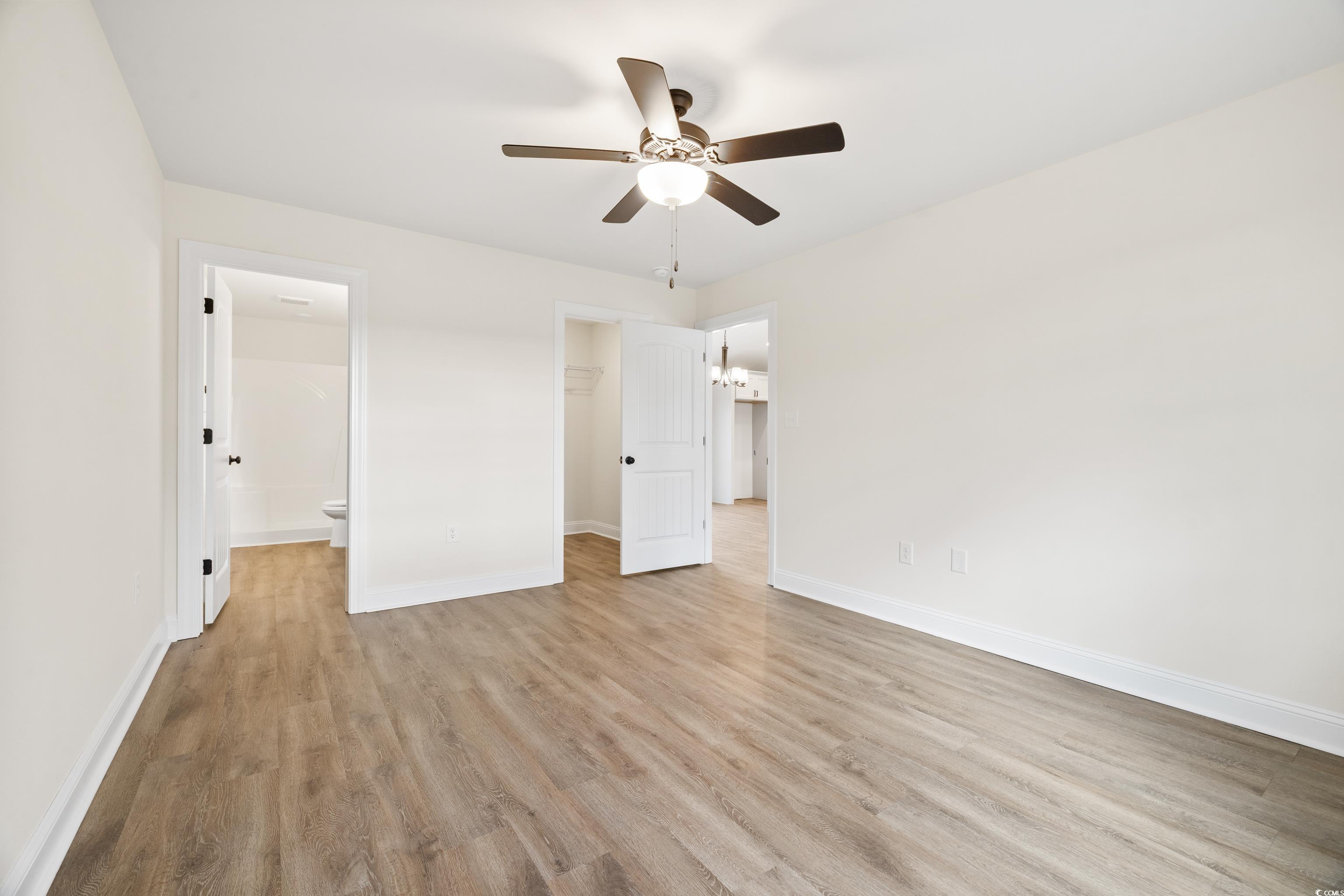 3640 Bethel Chapel Road Loris, SC 29569 - Photo 23 of 35 Unfurnished bedroom with a spacious closet, light wood-type flooring, ceiling fan, and connected bathroom