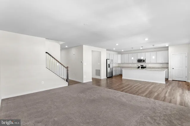 a kitchen with stainless steel appliances granite countertop a stove a sink and white cabinets with wooden floor