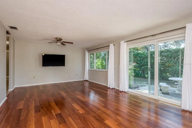 a view of empty room with wooden floor and fan