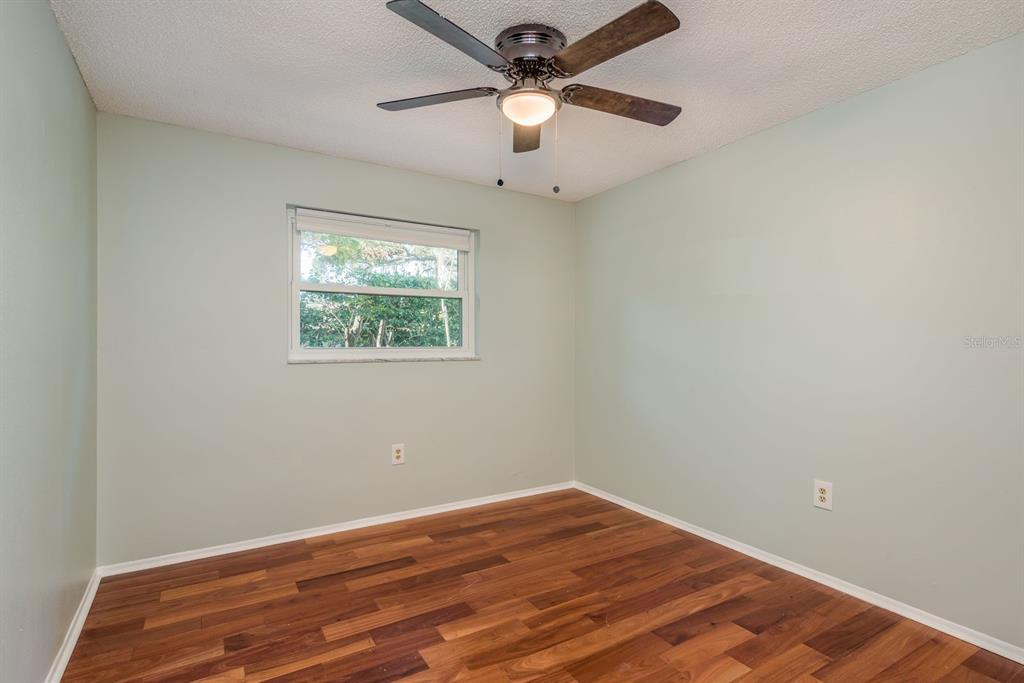 1104 Carlton Road Tarpon Springs, FL 34689 - Photo 20 of 35 an empty room with wooden floor ceiling fan and windows