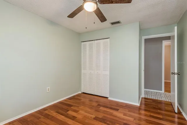 an empty room with wooden floor chandelier fan and closet area