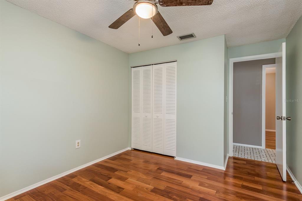 1104 Carlton Road Tarpon Springs, FL 34689 - Photo 21 of 35 an empty room with wooden floor chandelier fan and closet area