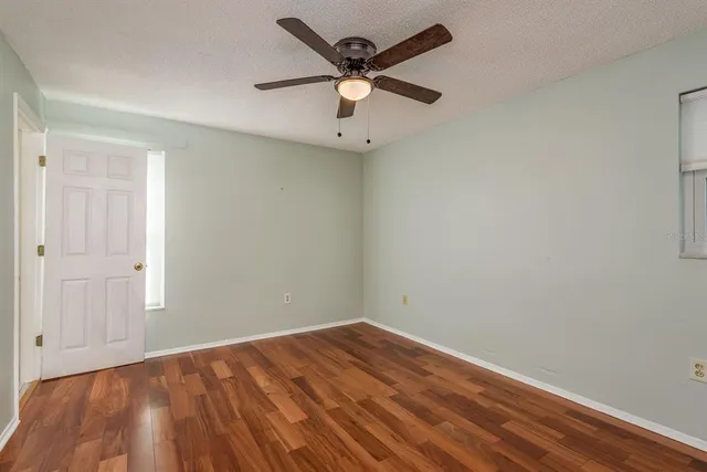 an empty room with a ceiling fan and wooden floor