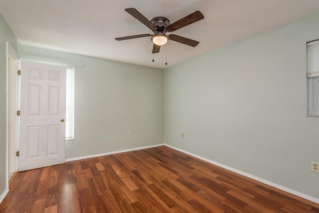 1104 Carlton Road Tarpon Springs, FL 34689 - Photo 23 of 35 an empty room with a ceiling fan and wooden floor