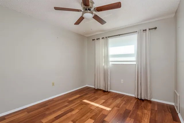 a view of empty room with wooden floor and fan