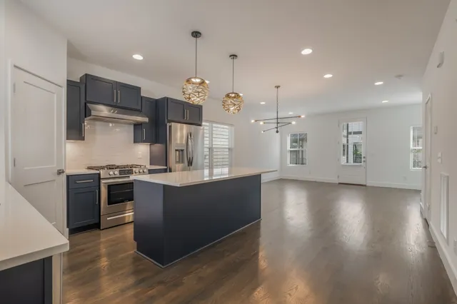 a large kitchen with stainless steel appliances kitchen island a large counter top and wooden floors