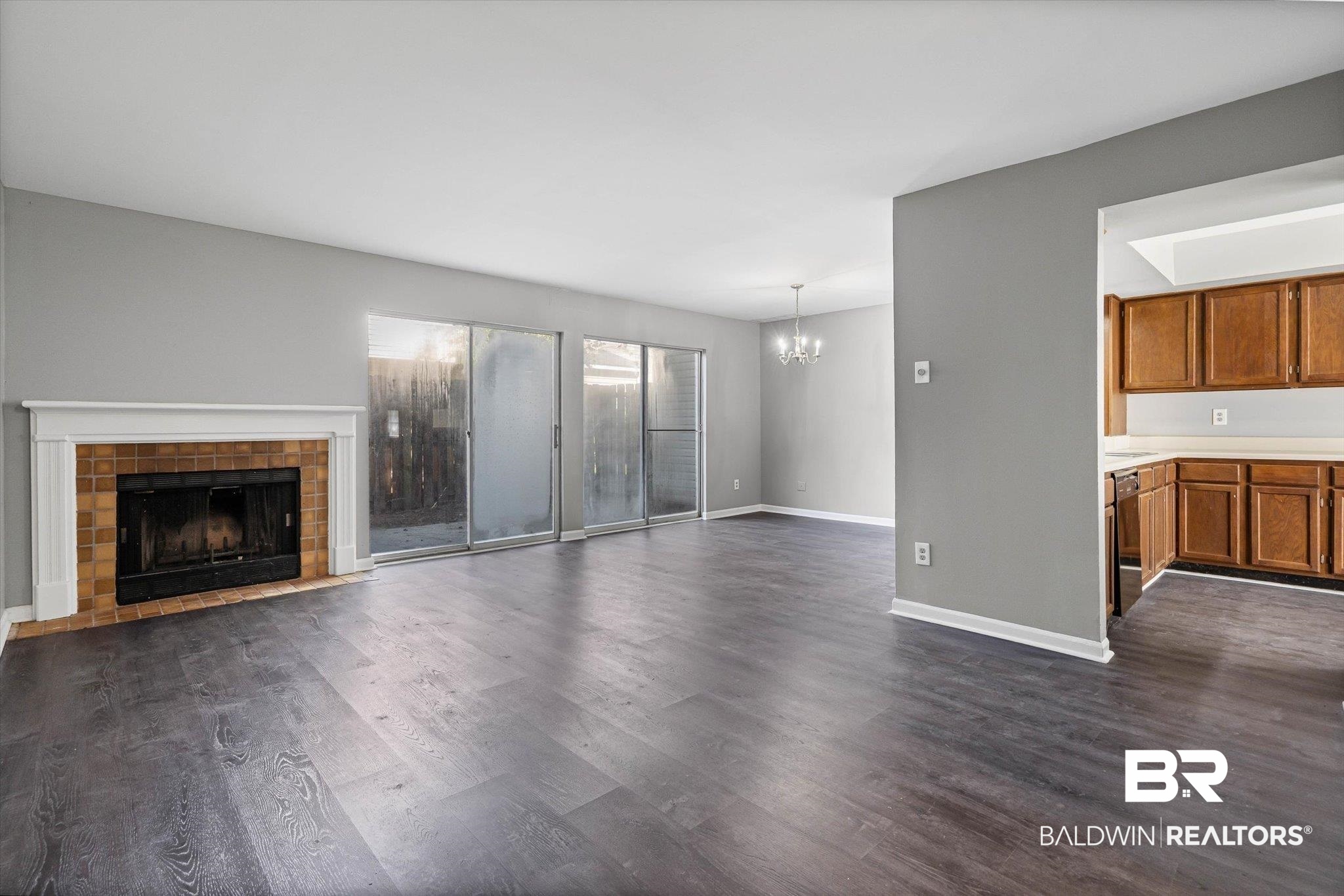 6701 Dickens Ferry Road, Unit 100 Mobile, AL 36608 - Photo 5 of 24 Unfurnished living room with dark wood-style floors, a chandelier, and a fireplace