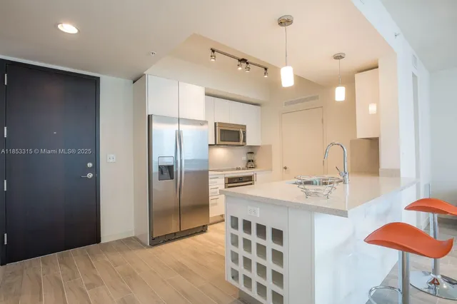 a kitchen with stainless steel appliances granite countertop a sink refrigerator and cabinets