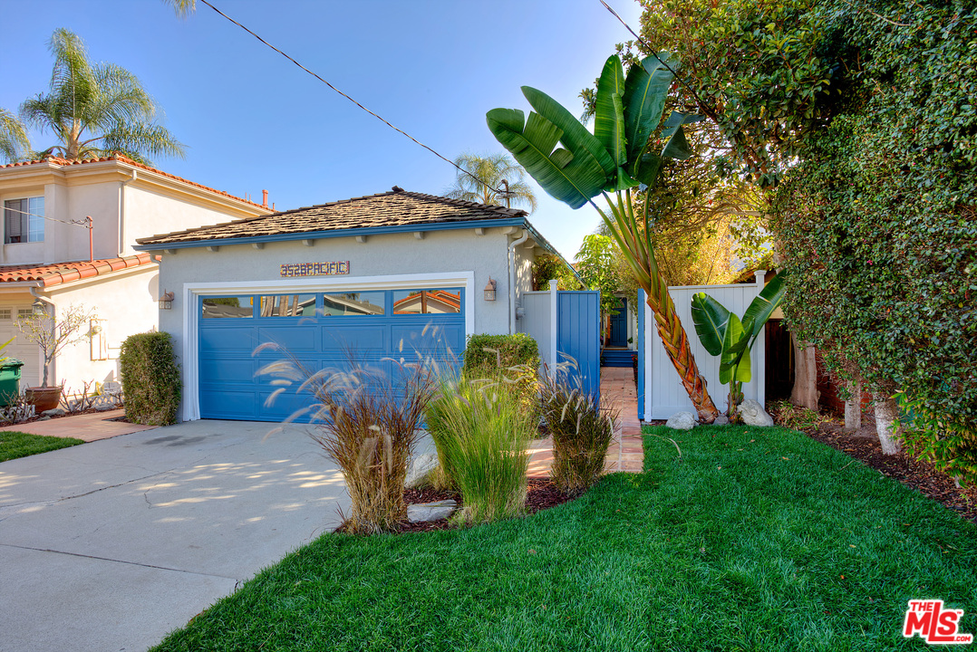 a view of a house with a small yard and a large tree