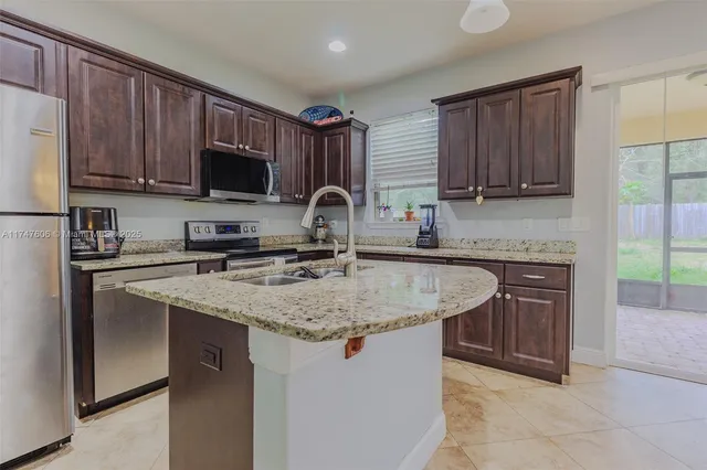 a kitchen with stainless steel appliances granite countertop a sink stove microwave and refrigerator