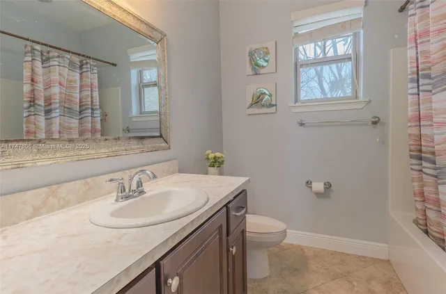 a bathroom with a granite countertop sink a toilet and a mirror