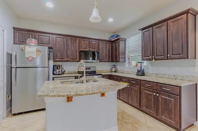 a kitchen with stainless steel appliances granite countertop a refrigerator stove microwave sink and cabinets
